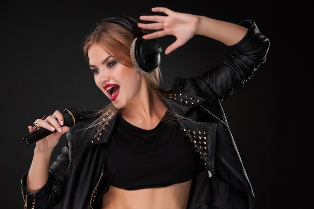 Portrait of a beautiful woman singing into microphone with headphones