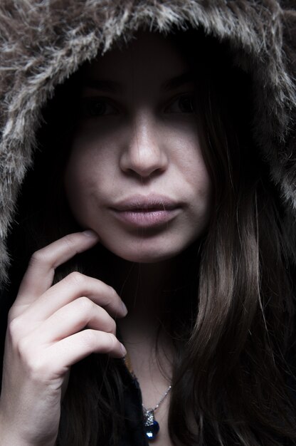 Portrait of beautiful woman standing and looking in black jacket with hairy hood