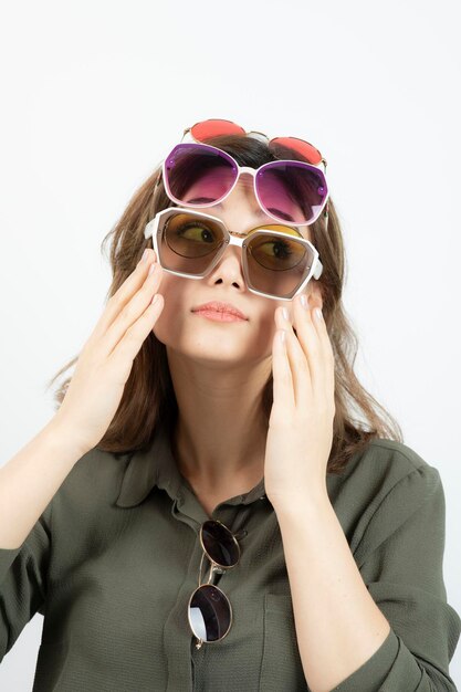 Portrait of beautiful woman wearing many sun glasses over white. High quality photo