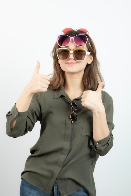 Portrait of beautiful woman wearing many sun glasses over white. High quality photo