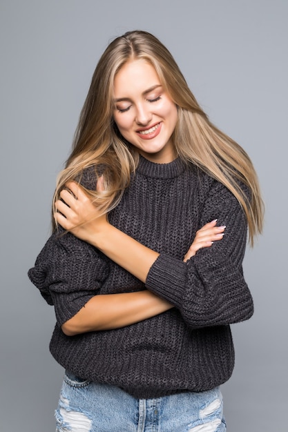 Free photo portrait of a beautiful woman wearing a warm knit sweater on her body on a gray background isolated