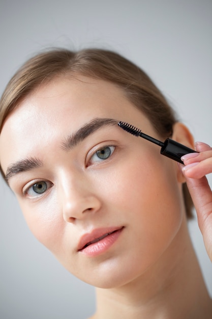 Portrait of beautiful woman with clear skin brushing her eyebrow