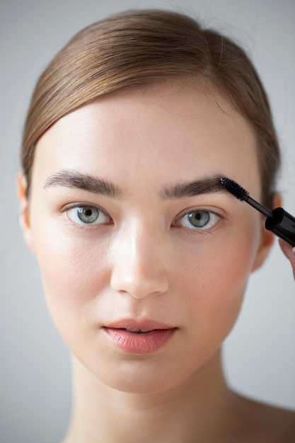 Portrait of beautiful woman with clear skin brushing her eyebrows