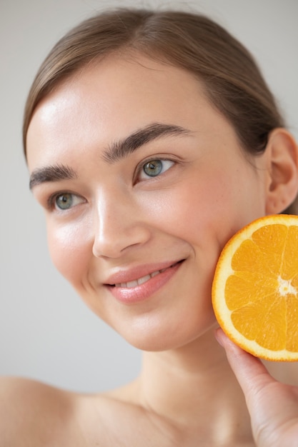 Free Photo portrait of beautiful woman with clear skin holding sliced orange fruit