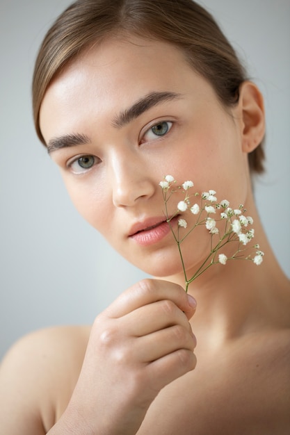 Free photo portrait of beautiful woman with clear skin posing with baby's breath flowers