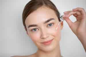 Free photo portrait of beautiful woman with clear skin using face serum