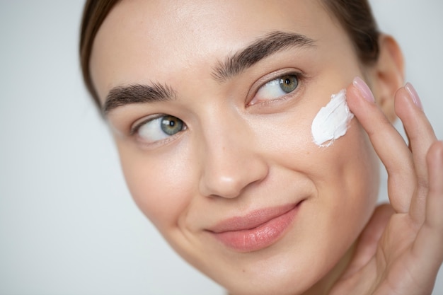 Portrait of beautiful woman with clear skin using moisturizer