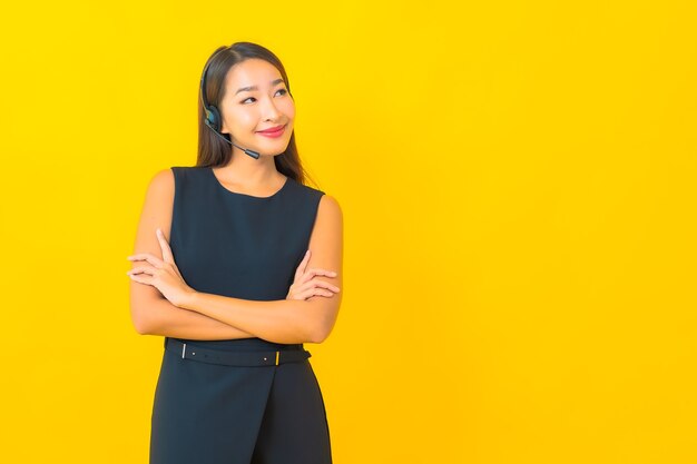 Portrait beautiful young asian business woman with headset call center customer care on yellow background