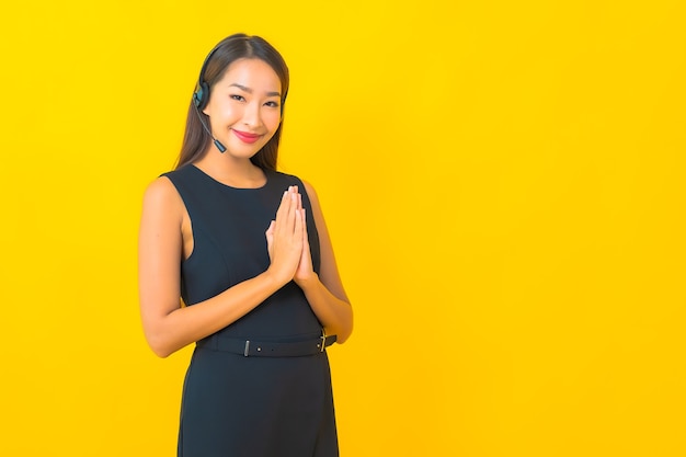 Portrait beautiful young asian business woman with headset call center customer care on yellow background