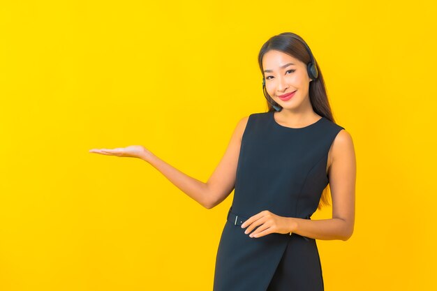 Portrait beautiful young asian business woman with headset call center customer care on yellow background