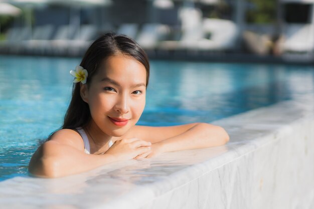 Portrait beautiful young asian woman happy smile in swimming pool around resort and hotel