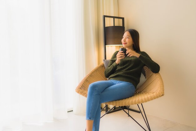 Portrait beautiful young asian woman hold coffee cup and sitting on sofa chair