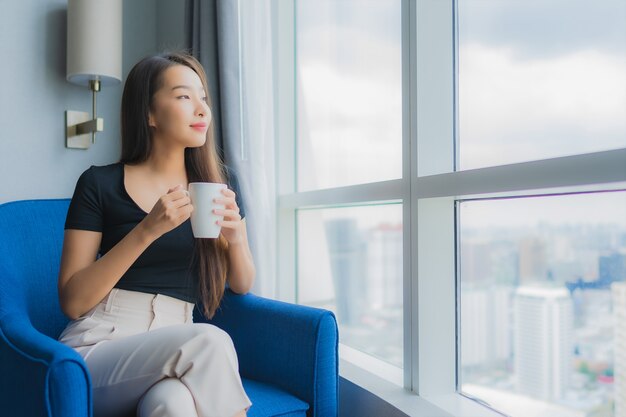 Portrait beautiful young asian woman hold coffee cup on sofa chair in living room area