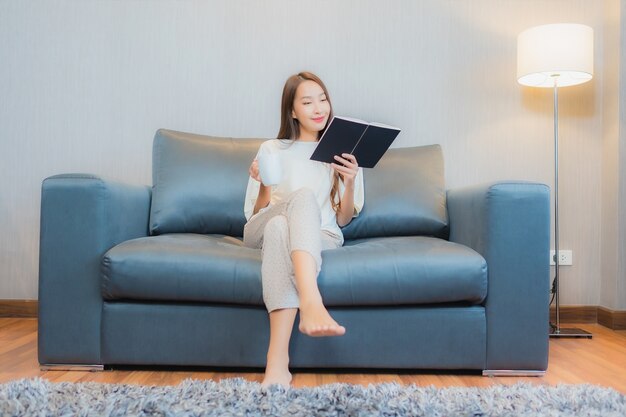 Portrait beautiful young asian woman read book on sofa in living room interior