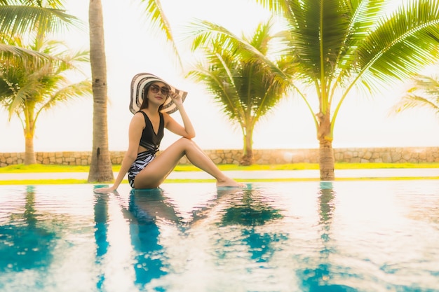 Free Photo portrait beautiful young asian woman relax around outdoor swimming pool in hotel resort with palm tree at sunset or sunrise