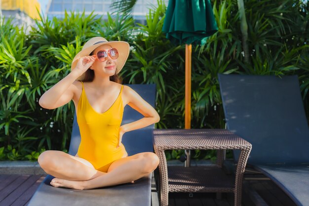 Portrait beautiful young asian woman relax happy smile around outdoor swimming pool in hotel resort for leisure vacation