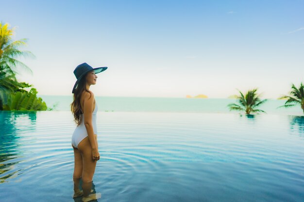 Portrait beautiful young asian woman relax in luxury outdoor swimming pool in hotel resort nearly beach sea ocean