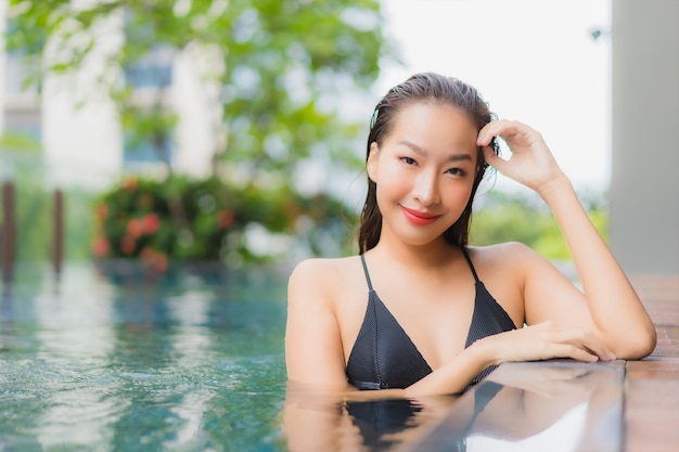 Free photo portrait beautiful young asian woman relax smile around outdoor swimming pool in hotel resort