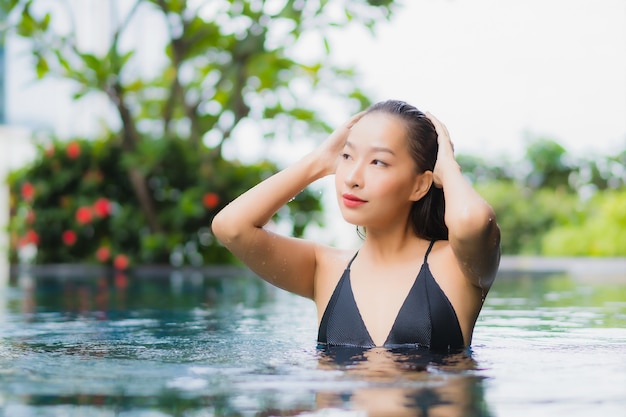 Free photo portrait beautiful young asian woman relax smile around outdoor swimming pool in hotel resort