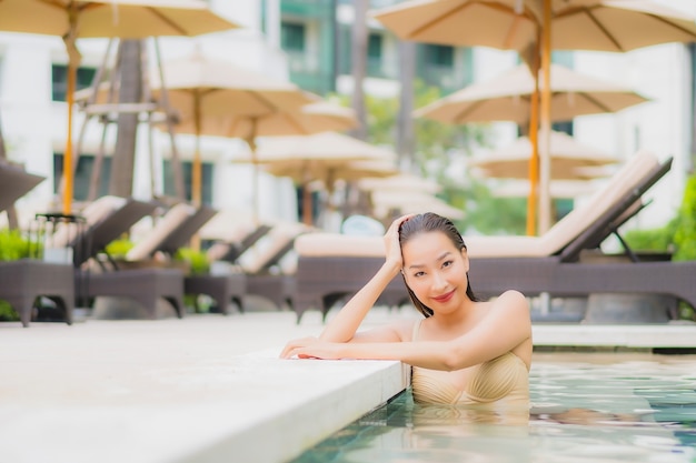 Portrait beautiful young asian woman relax smile around outdoor swimming pool in hotel resort