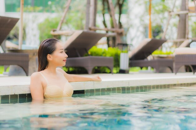 Portrait beautiful young asian woman relax smile around outdoor swimming pool in hotel resort