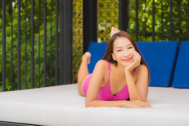 Free photo portrait beautiful young asian woman relax smile around outdoor swimming pool in hotel resort