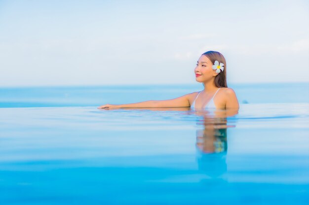 Portrait beautiful young asian woman relax smile around outdoor swimming pool in hotel resort