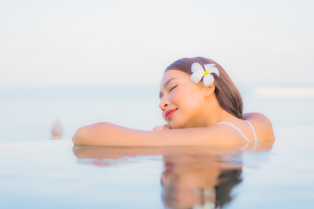 Portrait beautiful young asian woman relax smile around outdoor swimming pool in hotel resort