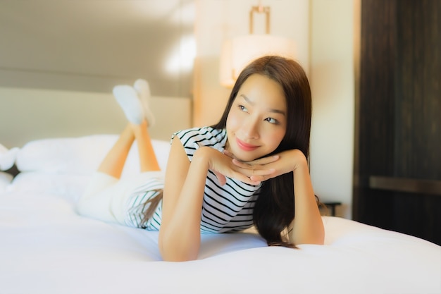 Portrait beautiful young asian woman relax smile on bed in bedroom interior