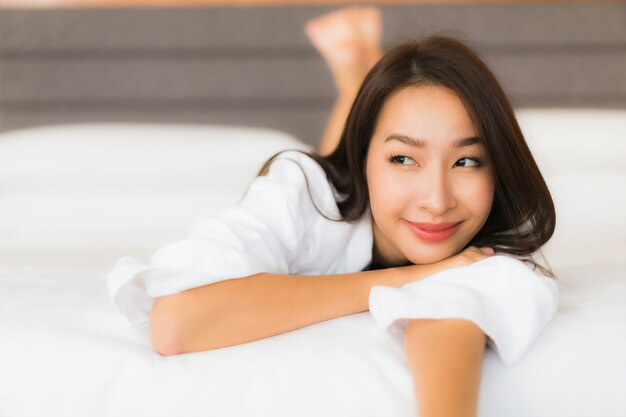 Portrait beautiful young asian woman relax smile on bed in bedroom interior