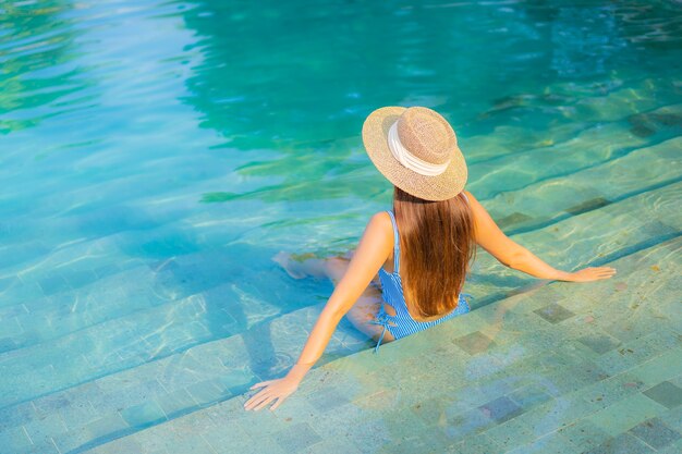 Portrait beautiful young asian woman relax smile enjoy leisure around swimming pool nearly sea beach ocean view on vacation