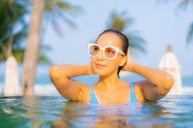 Portrait beautiful young asian woman relax smile enjoy leisure around swimming pool nearly sea beach ocean view on vacation