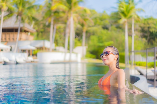 Portrait beautiful young asian woman relax smile leisure around outdoor swimming pool in resort hotel with sea ocean view