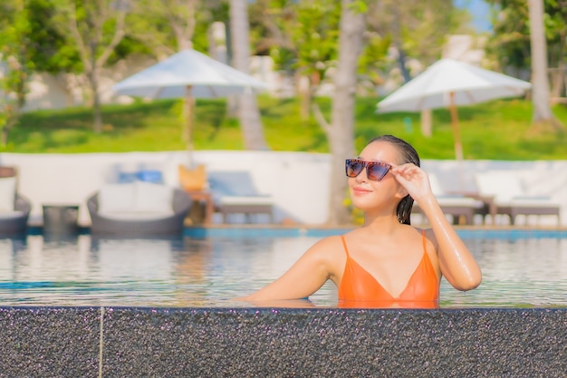 Portrait beautiful young asian woman relax smile leisure around outdoor swimming pool in resort hotel with sea ocean view