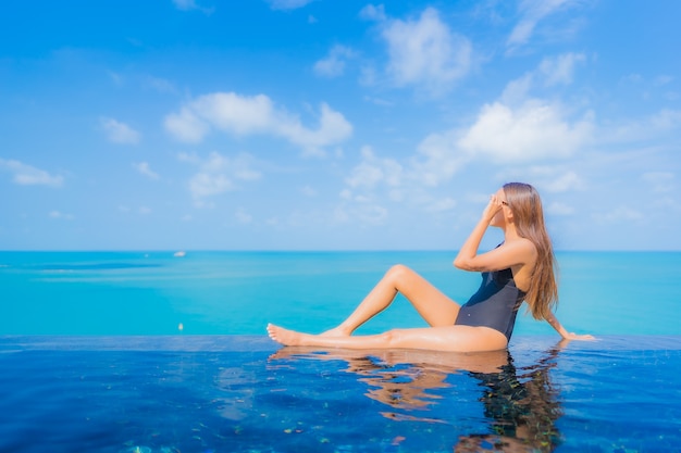 Portrait beautiful young asian woman relax smile leisure around outdoor swimming pool in resort hotel with sea ocean view