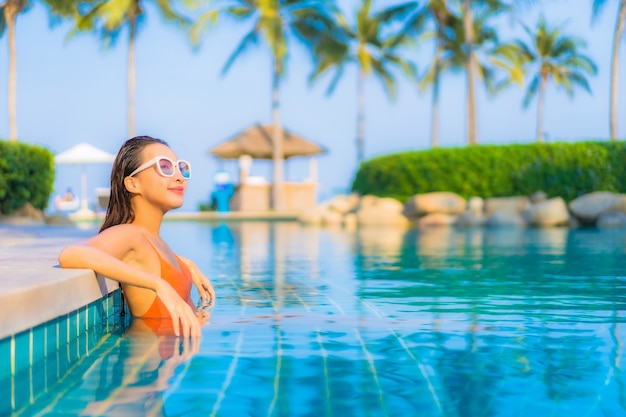 Portrait beautiful young asian woman relax smile leisure around outdoor swimming pool with sea ocean view