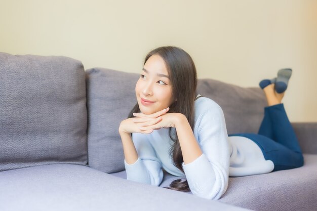 Portrait beautiful young asian woman relax smile on sofa in living room