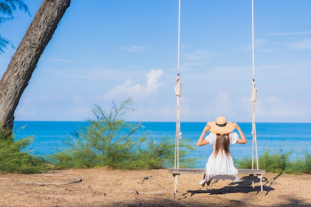 Portrait beautiful young asian woman relax smile on swing around beach sea ocean for nature travel in vacation