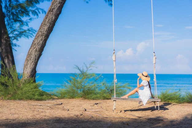 Portrait beautiful young asian woman relax smile on swing around beach sea ocean for nature travel in vacation