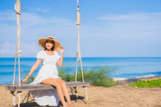 Portrait beautiful young asian woman relax smile on swing around beach sea ocean for nature travel in vacation