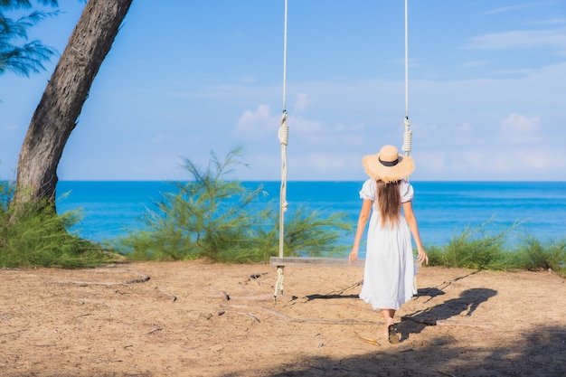 Portrait beautiful young asian woman relax smile on swing around beach sea ocean for nature travel in vacation