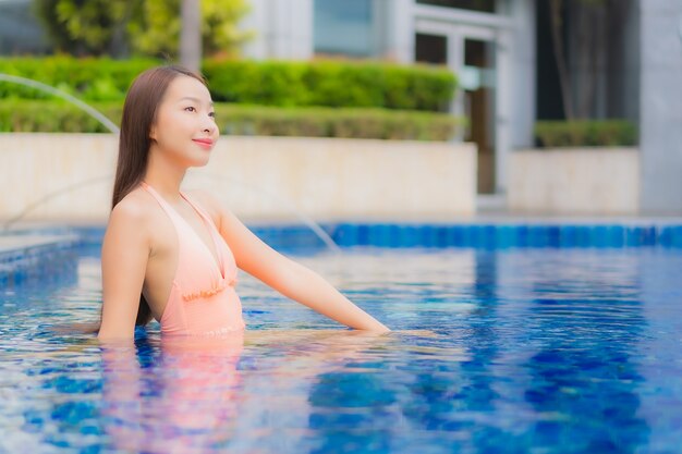 Portrait of beautiful young asian woman relaxes on the swimming pool in hotel resort