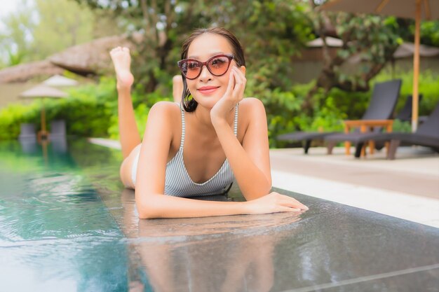 Portrait of beautiful young asian woman relaxing around outdoor swimming pool in hotel resort nearly sea