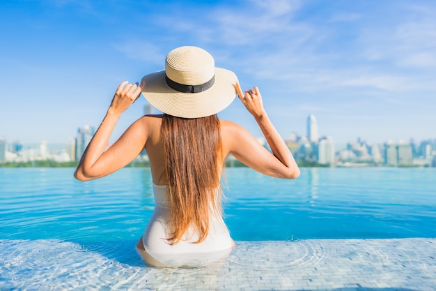 Portrait beautiful young asian woman relaxing around outdoor swimming pool with city view