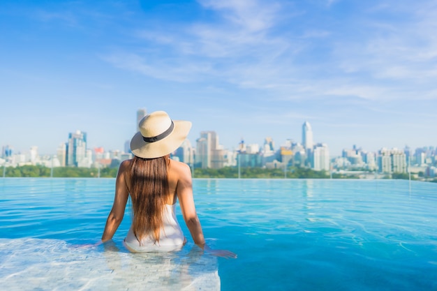 Free photo portrait beautiful young asian woman relaxing around outdoor swimming pool with city view