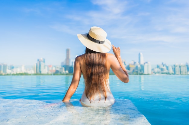 Portrait beautiful young asian woman relaxing around outdoor swimming pool with city view