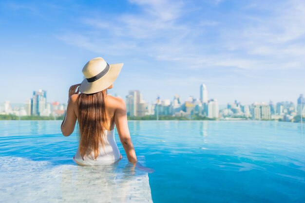 Portrait beautiful young asian woman relaxing around outdoor swimming pool with city view