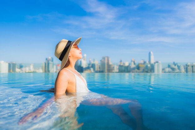 Portrait beautiful young asian woman relaxing around outdoor swimming pool with city view