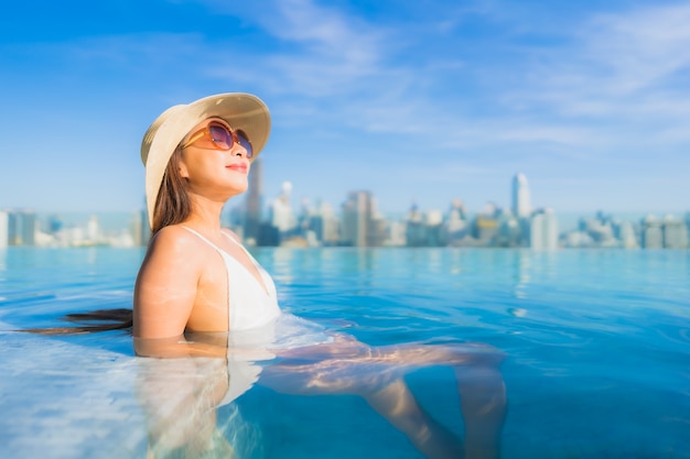 Free photo portrait beautiful young asian woman relaxing around outdoor swimming pool with city view