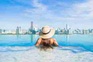 Free photo portrait beautiful young asian woman relaxing around outdoor swimming pool with city view